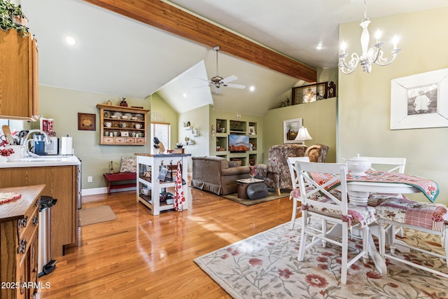 dining area featuring ceiling fan with notable chandelier, sink, light hardwood / wood-style flooring, and vaulted ceiling with beams