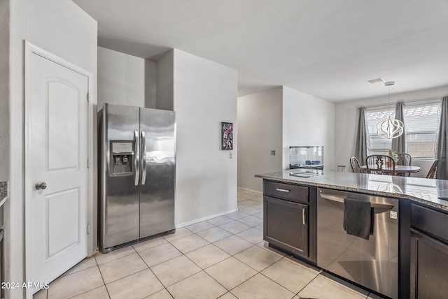 kitchen with dark brown cabinets, pendant lighting, stainless steel appliances, and dark stone counters