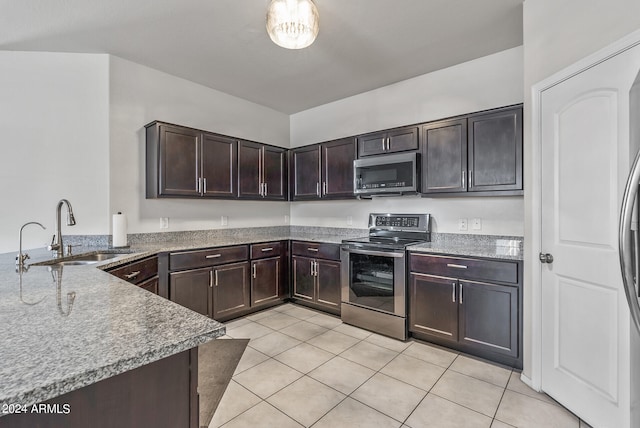 kitchen featuring light tile patterned flooring, sink, kitchen peninsula, dark brown cabinets, and appliances with stainless steel finishes