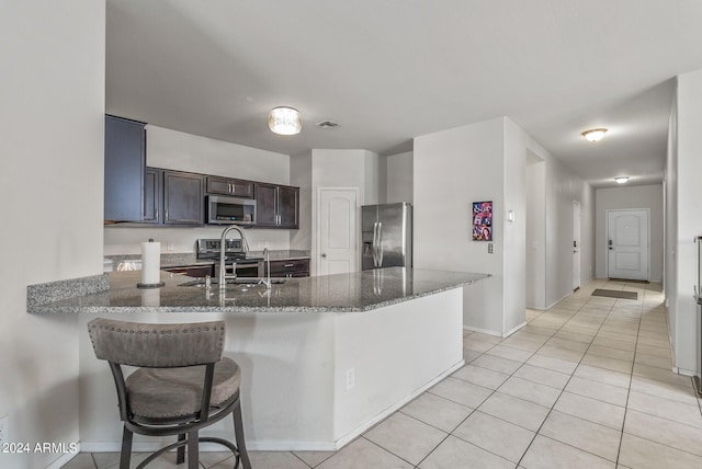 kitchen featuring dark stone counters, sink, stainless steel appliances, light tile patterned floors, and dark brown cabinetry