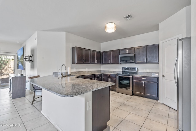 kitchen featuring light tile patterned flooring, sink, kitchen peninsula, appliances with stainless steel finishes, and a kitchen breakfast bar