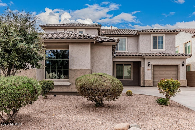 view of front of home with a tiled roof, stucco siding, driveway, and a garage