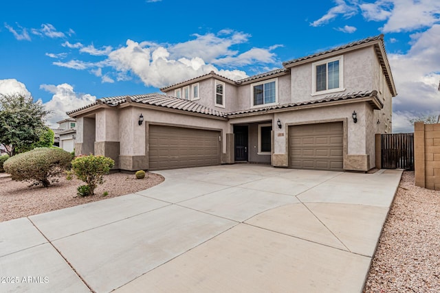 mediterranean / spanish-style house with stucco siding, fence, concrete driveway, and a tile roof