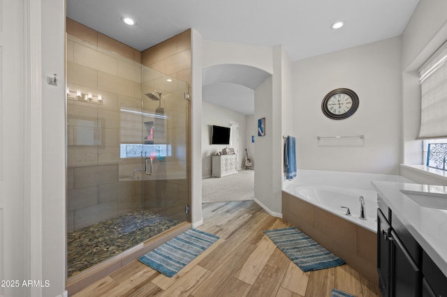 bathroom featuring a stall shower, wood finished floors, recessed lighting, a bath, and vanity