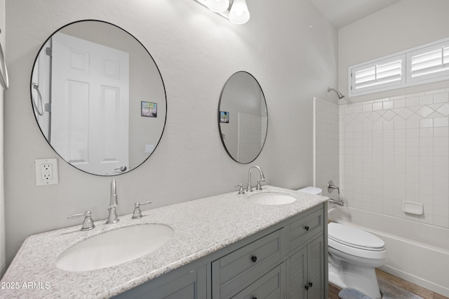 bathroom featuring  shower combination, toilet, double vanity, and a sink