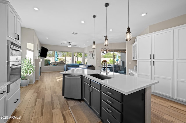 kitchen with a sink, appliances with stainless steel finishes, white cabinets, and light countertops