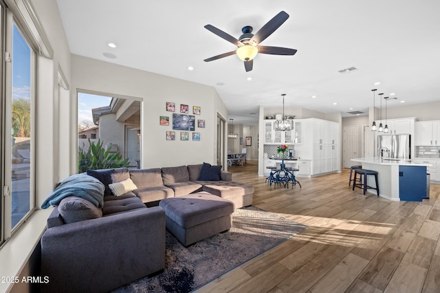 living room featuring recessed lighting, visible vents, light wood-style floors, and ceiling fan with notable chandelier