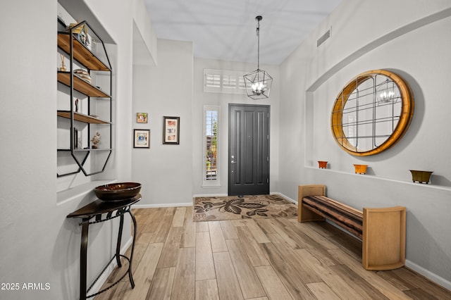 entrance foyer featuring visible vents, baseboards, a notable chandelier, and wood finished floors