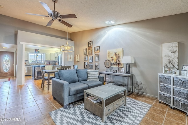 living room with ceiling fan, vaulted ceiling, tile patterned floors, and a textured ceiling