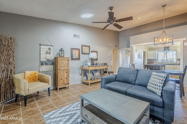 living room with ceiling fan with notable chandelier, lofted ceiling, tile patterned flooring, and a textured ceiling