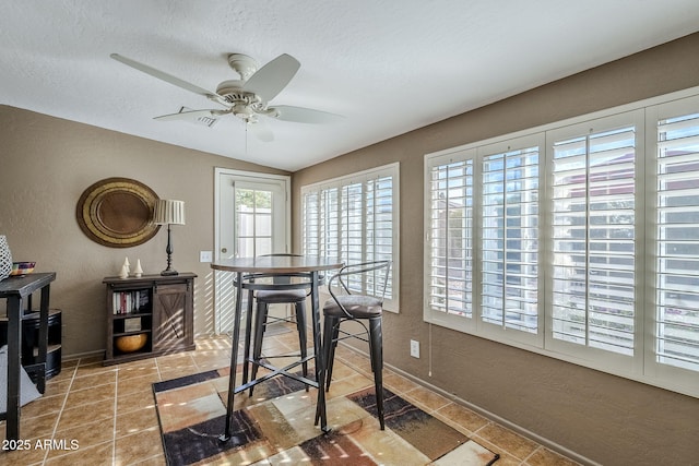 dining area with lofted ceiling, ceiling fan, and a textured ceiling