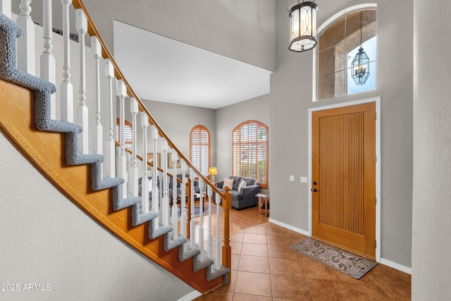 tiled foyer entrance with a chandelier and a high ceiling