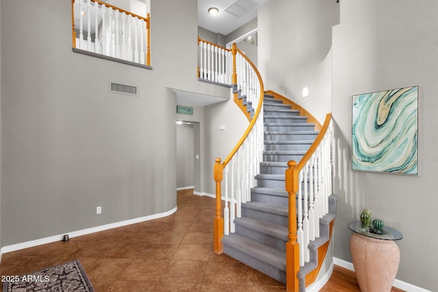 stairway featuring tile patterned floors and a high ceiling