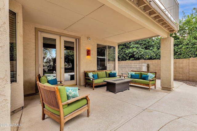 view of patio with a balcony, french doors, and an outdoor living space with a fire pit