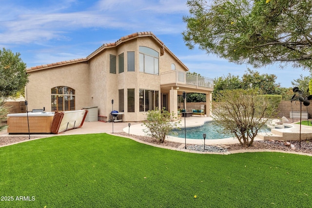 rear view of house with a pool with hot tub, a yard, a balcony, and a patio