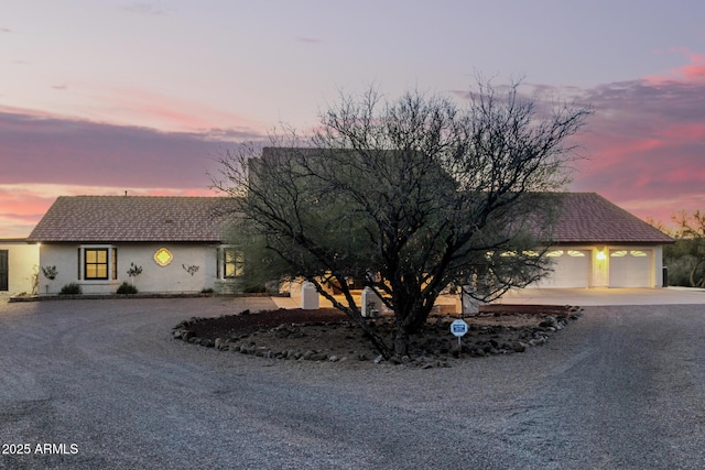 ranch-style house with driveway, a garage, and stucco siding