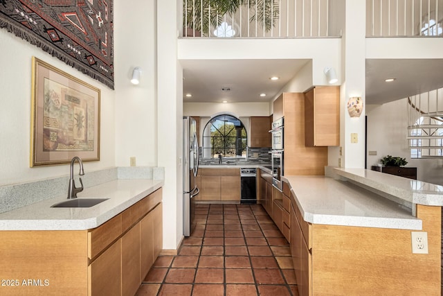 kitchen featuring light tile patterned floors, a towering ceiling, freestanding refrigerator, a sink, and backsplash