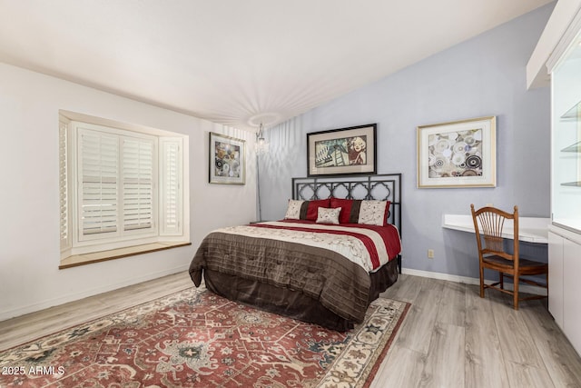 bedroom featuring lofted ceiling, wood finished floors, and baseboards