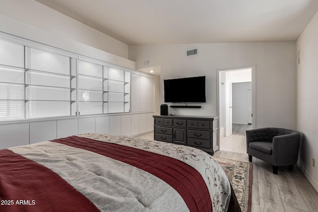 bedroom with lofted ceiling, light wood-style flooring, and visible vents