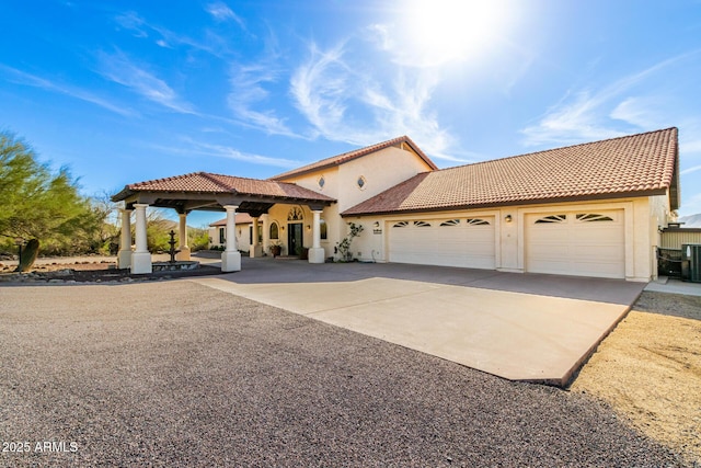 mediterranean / spanish house with driveway, an attached garage, a tile roof, and stucco siding