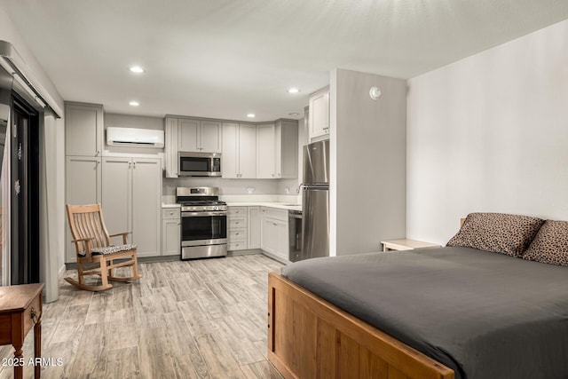 bedroom with light wood finished floors, recessed lighting, a wall mounted air conditioner, and freestanding refrigerator