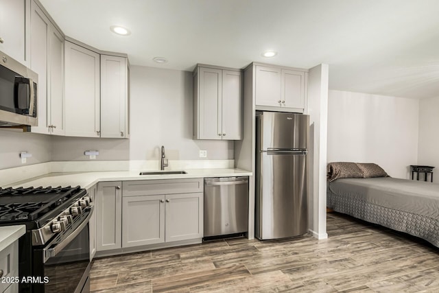 kitchen with light wood finished floors, appliances with stainless steel finishes, gray cabinets, and a sink