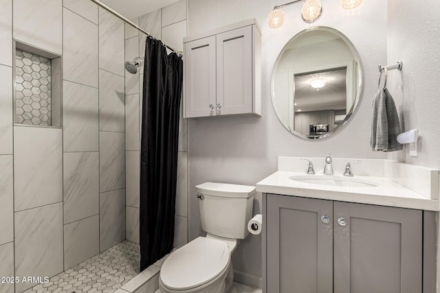 bathroom featuring a tile shower, vanity, and toilet