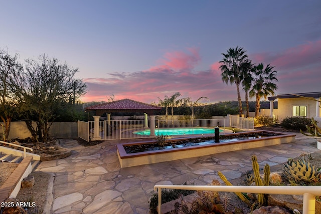 pool at dusk featuring a gazebo, a fenced backyard, a fenced in pool, and a patio