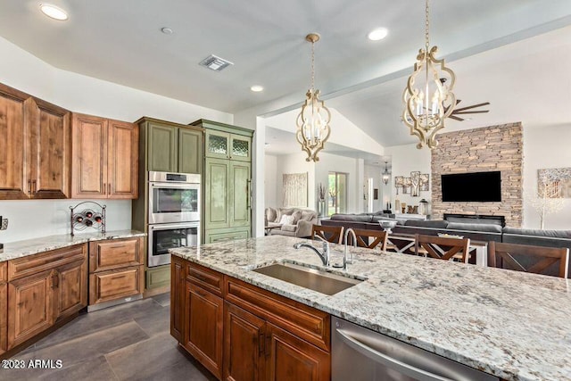 kitchen with lofted ceiling, hanging light fixtures, sink, appliances with stainless steel finishes, and a notable chandelier