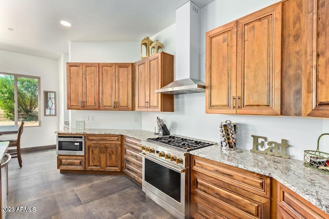 kitchen with light stone countertops, stainless steel appliances, and wall chimney range hood