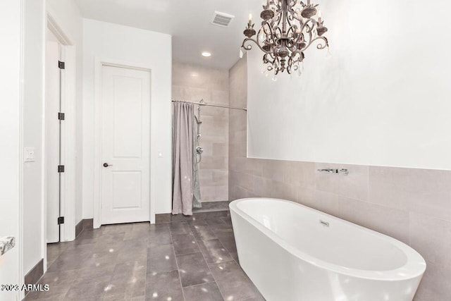 bathroom featuring plus walk in shower, tile walls, and an inviting chandelier
