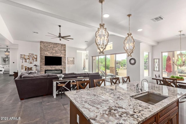 kitchen featuring light stone countertops, a breakfast bar, decorative light fixtures, and sink