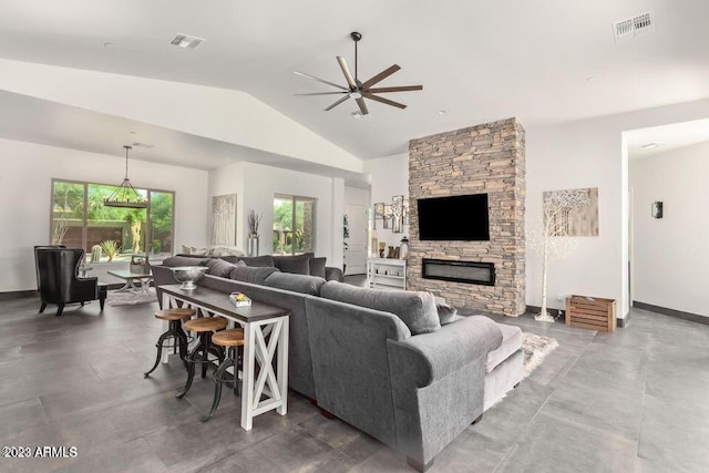 living room with ceiling fan, a stone fireplace, and lofted ceiling