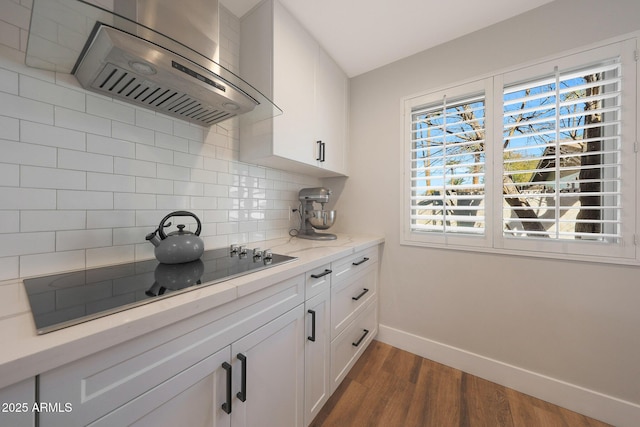 kitchen featuring dark wood finished floors, range hood, white cabinetry, black electric cooktop, and baseboards