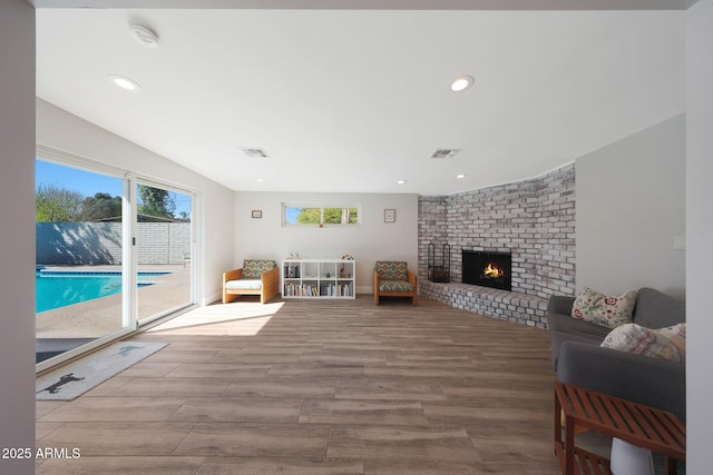 living room with visible vents, recessed lighting, a fireplace, and wood finished floors