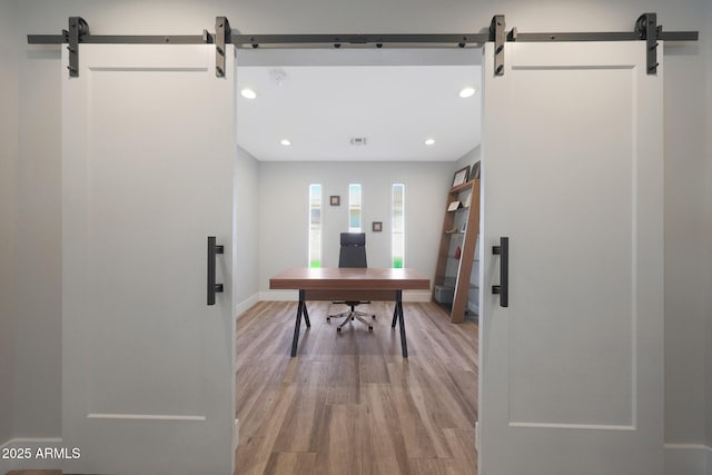 home office featuring light wood-type flooring, a barn door, baseboards, and recessed lighting