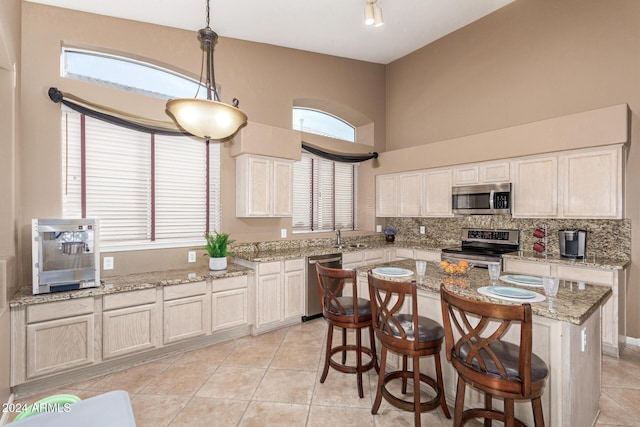 kitchen with decorative light fixtures, stainless steel appliances, a kitchen island, and a wealth of natural light