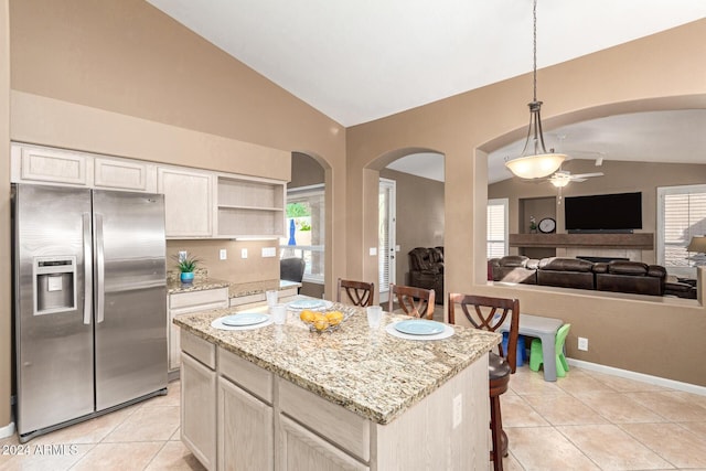 kitchen featuring ceiling fan, stainless steel fridge, lofted ceiling, a breakfast bar area, and a kitchen island