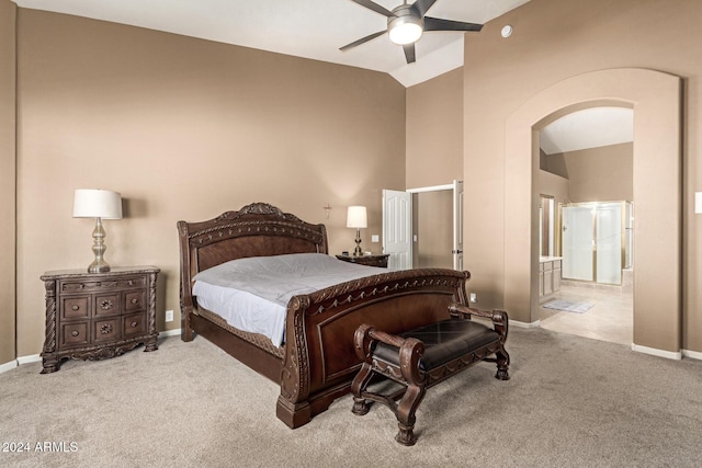 carpeted bedroom with ceiling fan, lofted ceiling, and ensuite bath