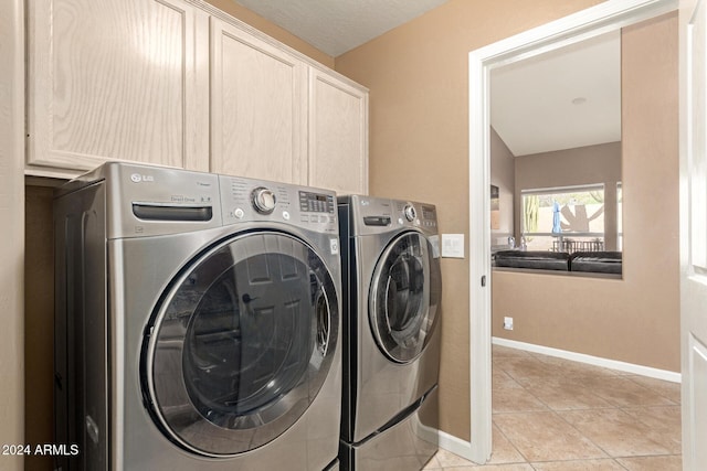 laundry area with cabinets, light tile patterned floors, and washing machine and clothes dryer