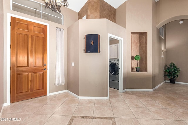 tiled foyer with high vaulted ceiling, a chandelier, and washer / dryer