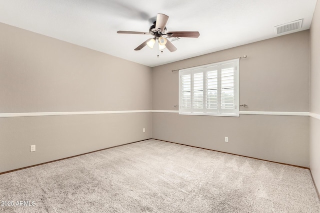 carpeted spare room with visible vents and a ceiling fan