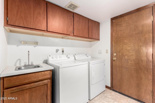 washroom with cabinet space, visible vents, washing machine and dryer, a sink, and light tile patterned flooring