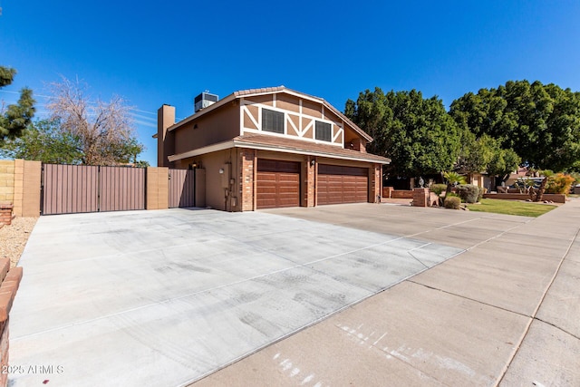 chalet / cabin featuring an attached garage, central air condition unit, brick siding, fence, and concrete driveway