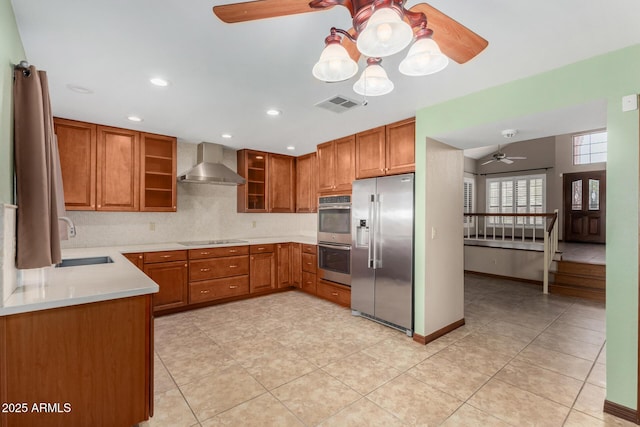 kitchen featuring visible vents, light countertops, appliances with stainless steel finishes, a sink, and wall chimney range hood