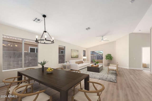 dining space featuring ceiling fan with notable chandelier, light wood-type flooring, and lofted ceiling