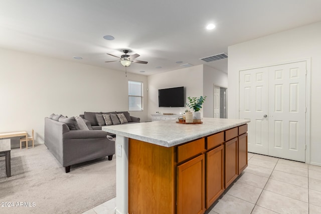 kitchen with light carpet, a kitchen island, and ceiling fan