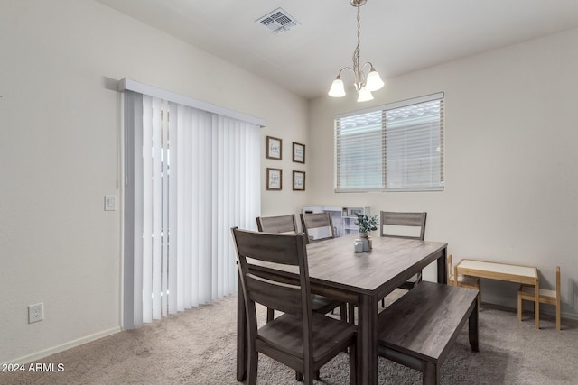 carpeted dining area with a chandelier