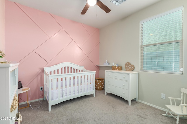 carpeted bedroom with a nursery area and ceiling fan