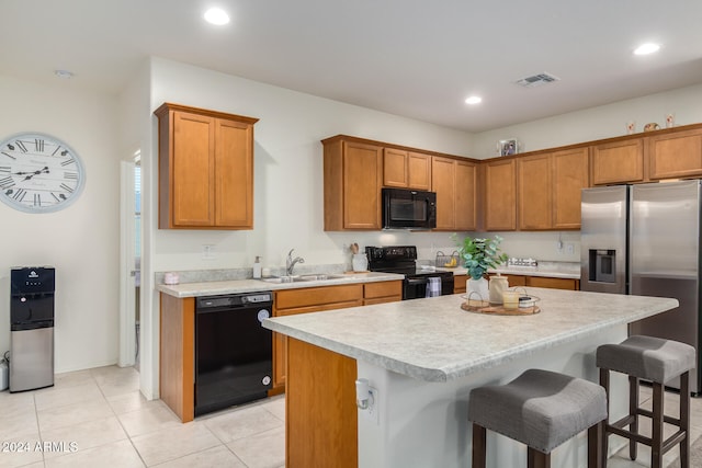 kitchen with black appliances, a kitchen island, sink, and a kitchen breakfast bar